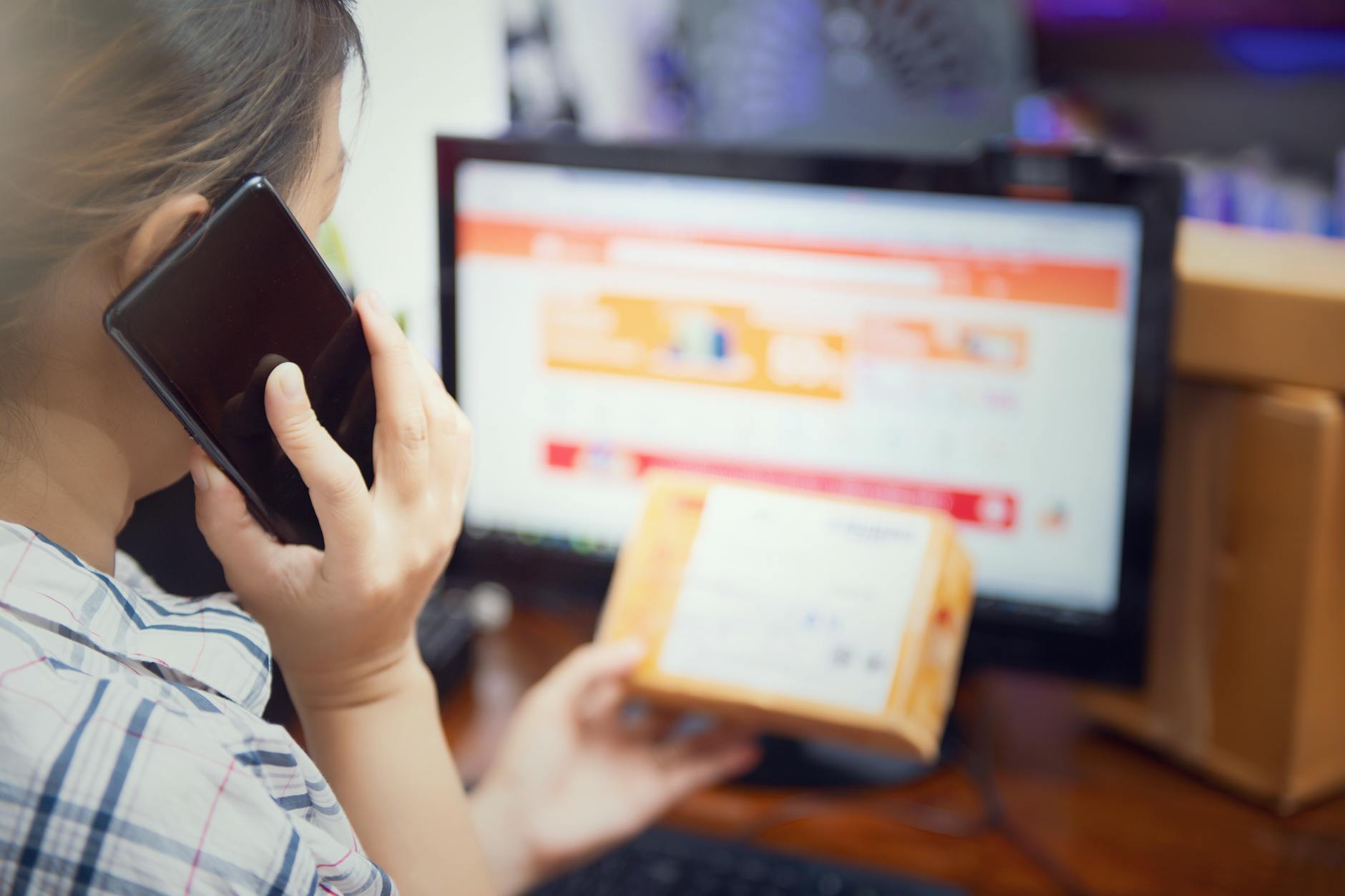 Kobieta w domu sprawdza paczkę z zamówieniem online i rozmawia przez telefon