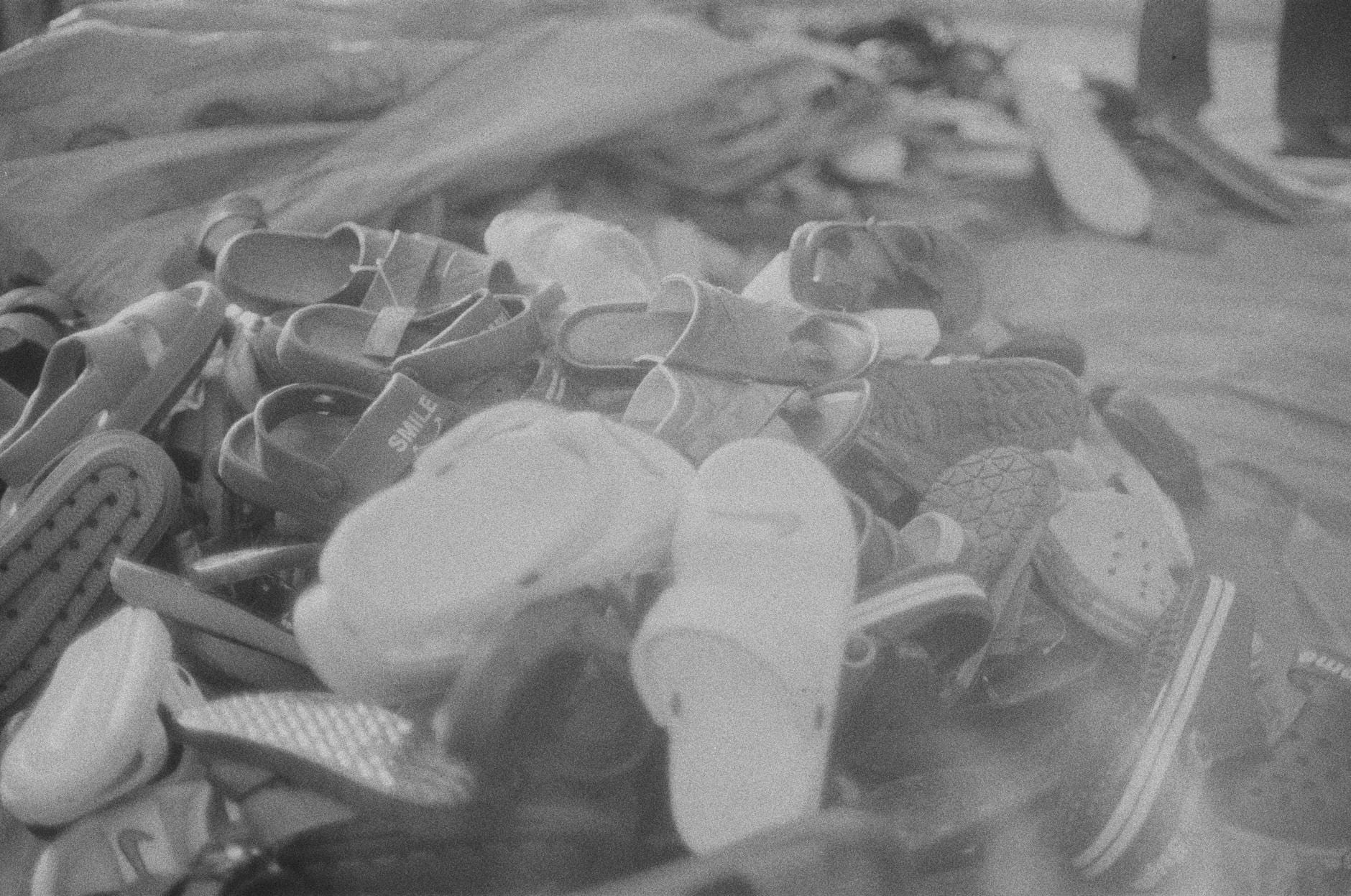 Stos sandałów i klapek używanych ułożonych na ziemi