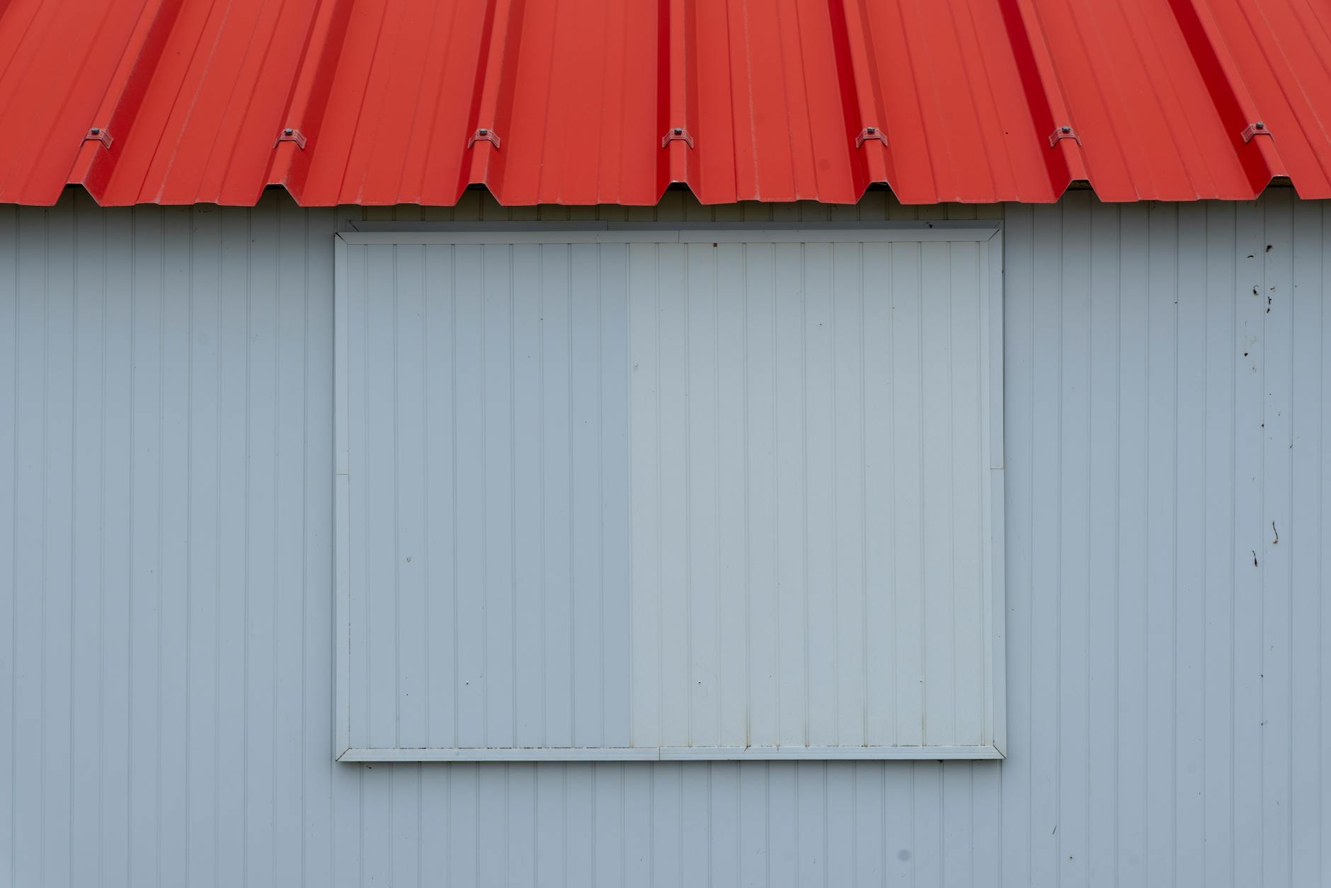 Czerwony dach z blachy i ściana z niebieskoszarej blachy trapezowej