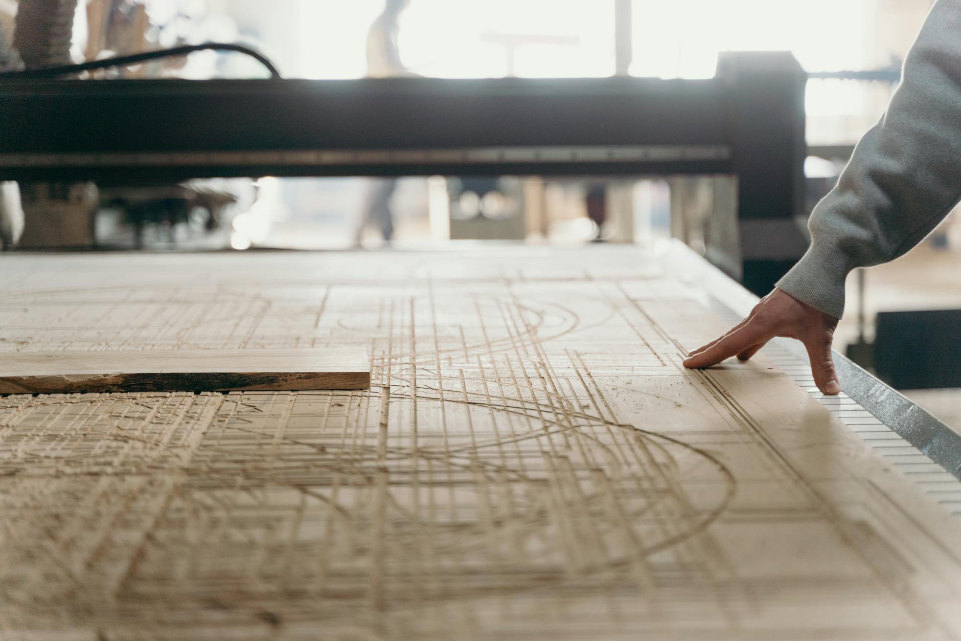 Dłoń dotyka obrabianego kawałka drewna w warsztacie stolarskim