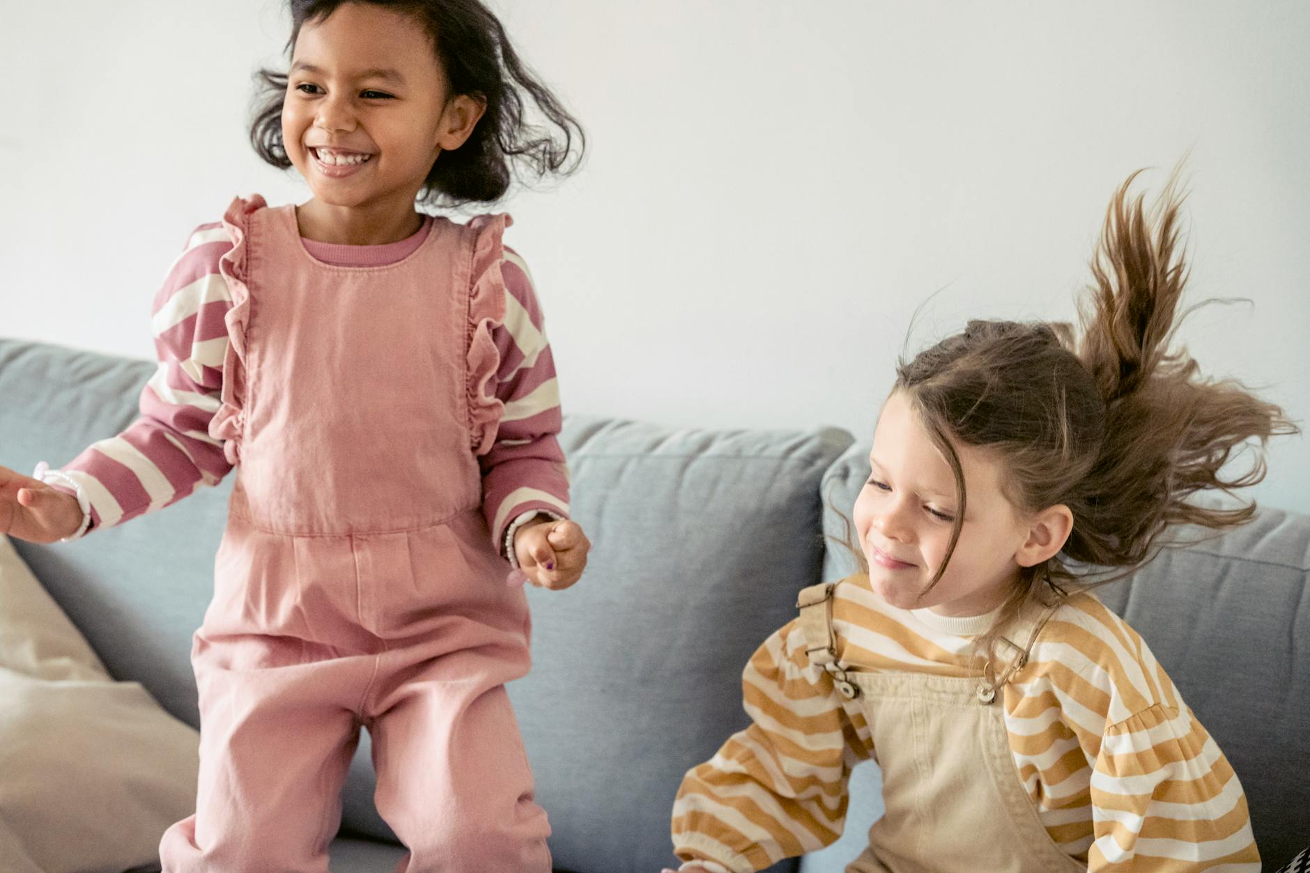 Małe dziewczynki w różnym wieku skaczą radośnie na kanapie