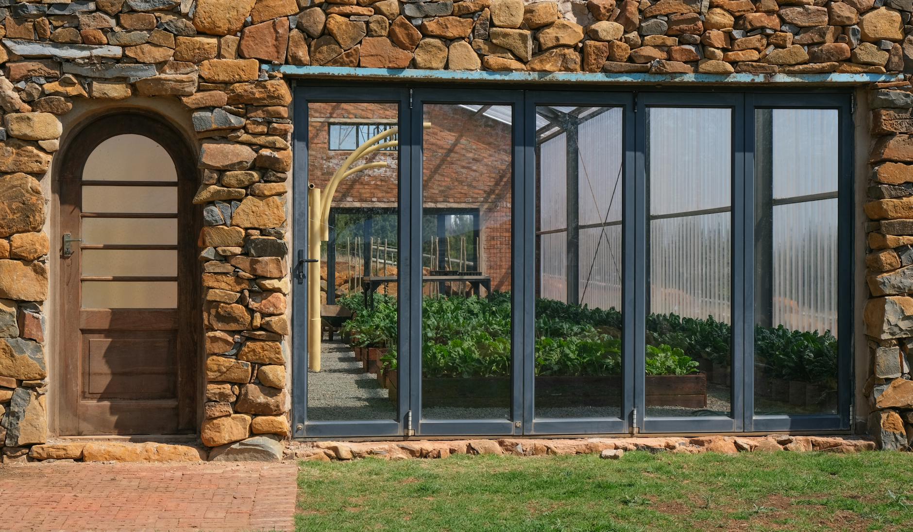 Rustykalna szklarnia z kamiennym murem i dużymi oknami z widocznymi roślinami