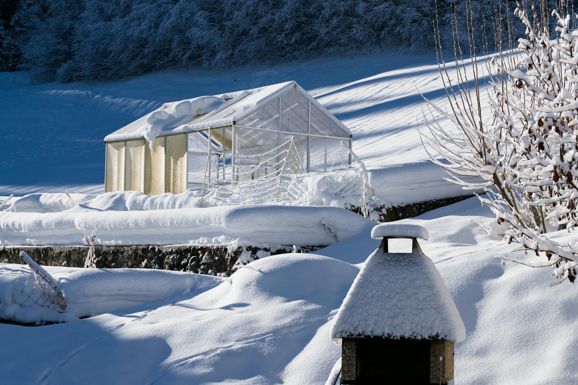 Ośnieżona szklarnia w zimowym krajobrazie górskiej wsi