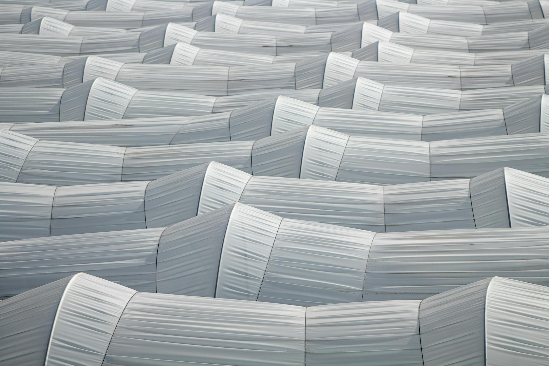 Szeregi tunelowych szklarni widziane z lotu ptaka na polu