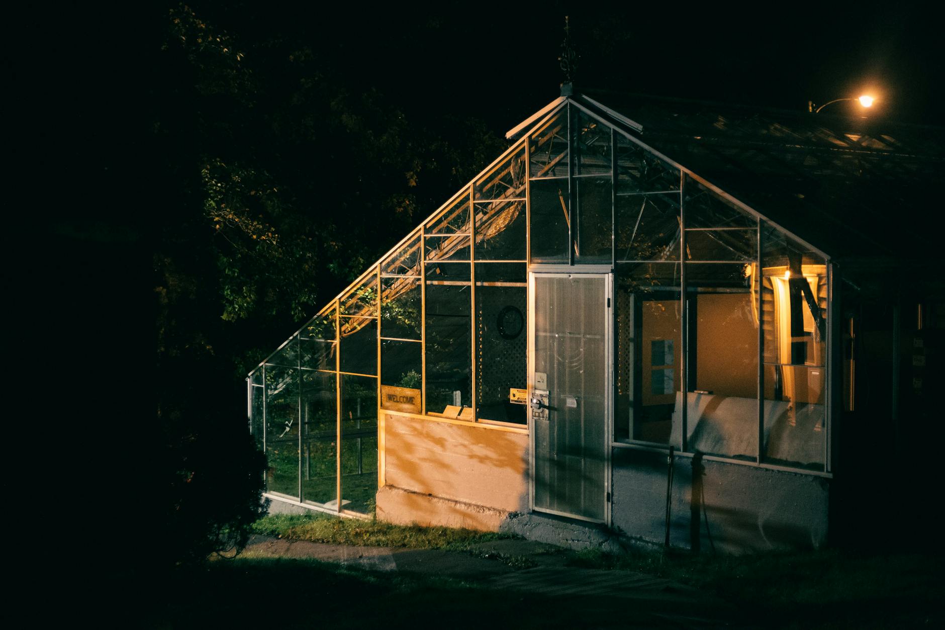 Drewniana szklarnia z podświetlonymi taflami szkła nocą