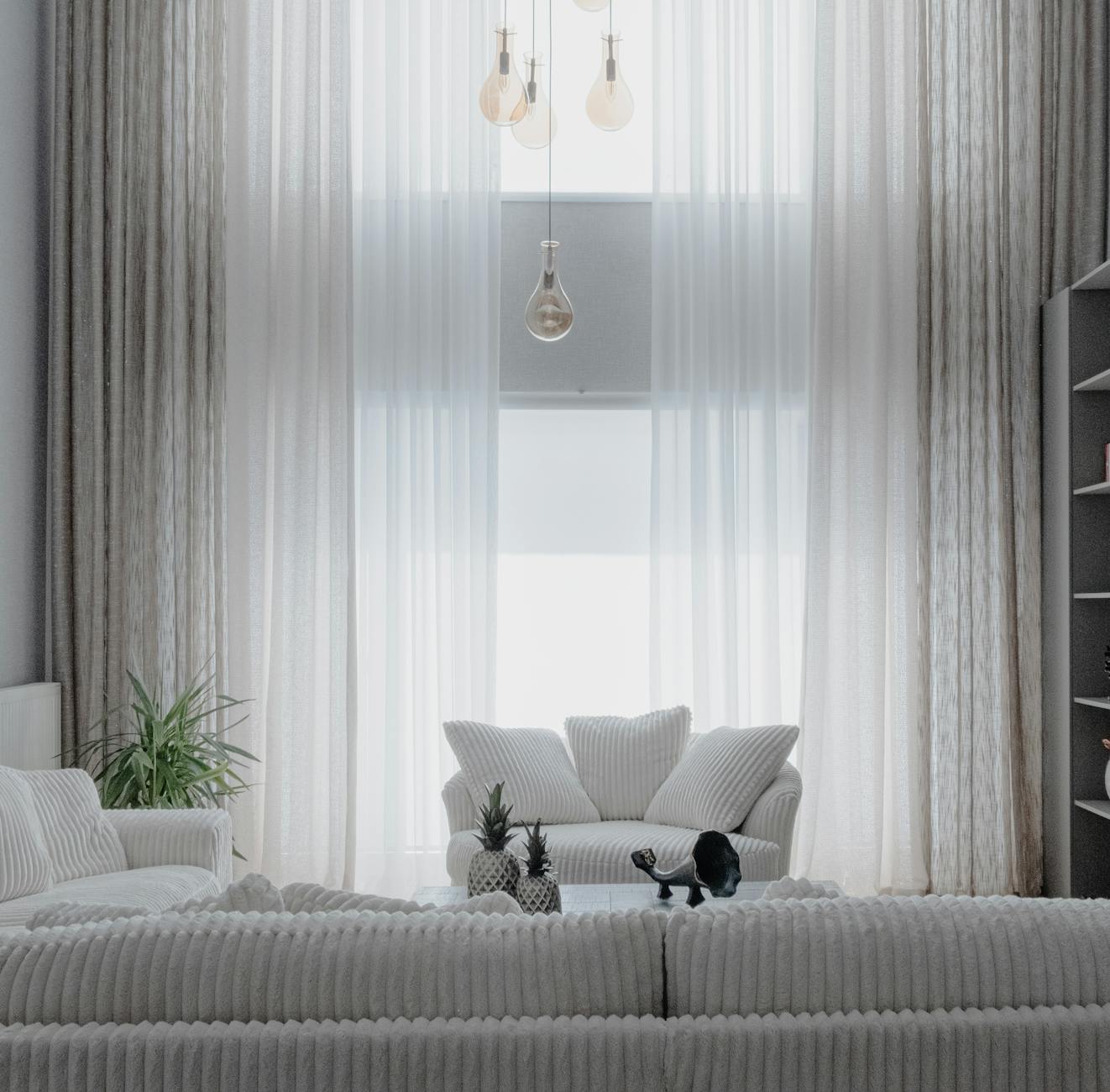 Minimalistyczny salon z białymi sofami i wysokimi zasłonami