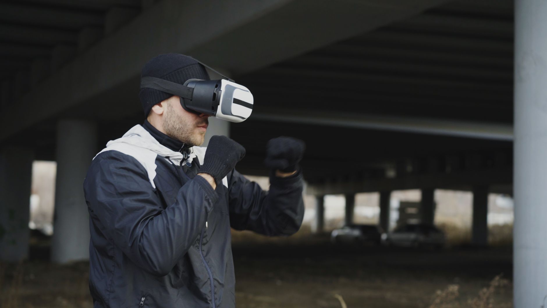 Mężczyzna trenuje boks w goglach VR pod mostem na świeżym powietrzu