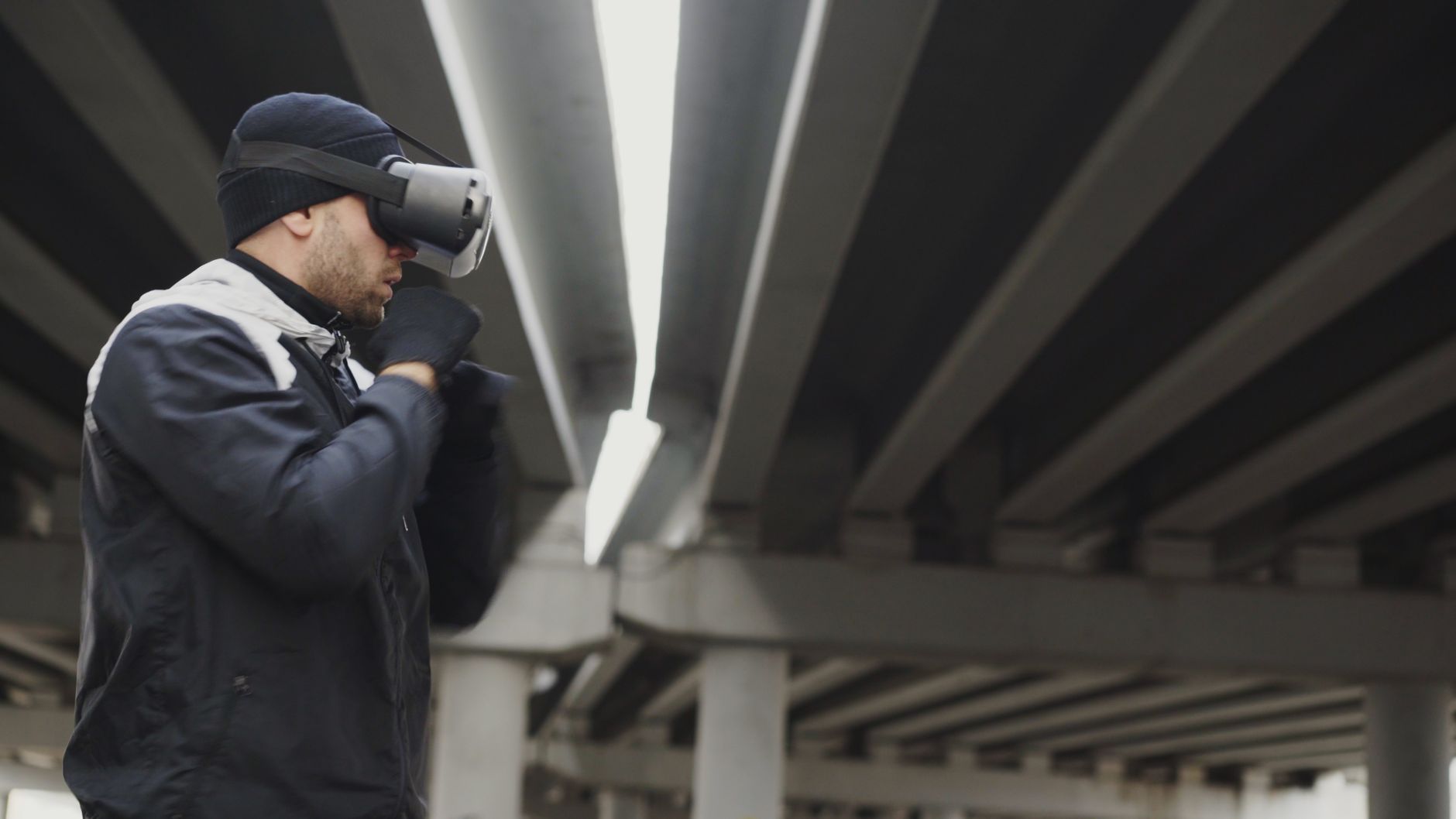 Mężczyzna w goglach VR trenuje boks pod betonowym wiaduktem